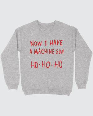 Now I Have A Machine Gun Ho Ho Ho ugly sweater in Sport Grey, flat lay on grey
